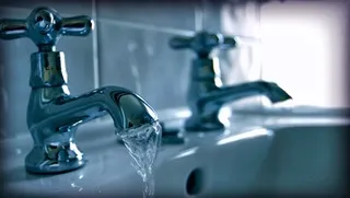 Close-up of a bathroom tap running water into a sink.
