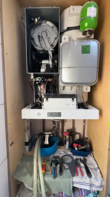 Combi boiler service in progress with casing open and tools ready for maintenance checks