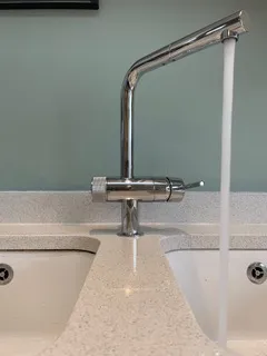 Kitchen mixer tap running water over a double sink.