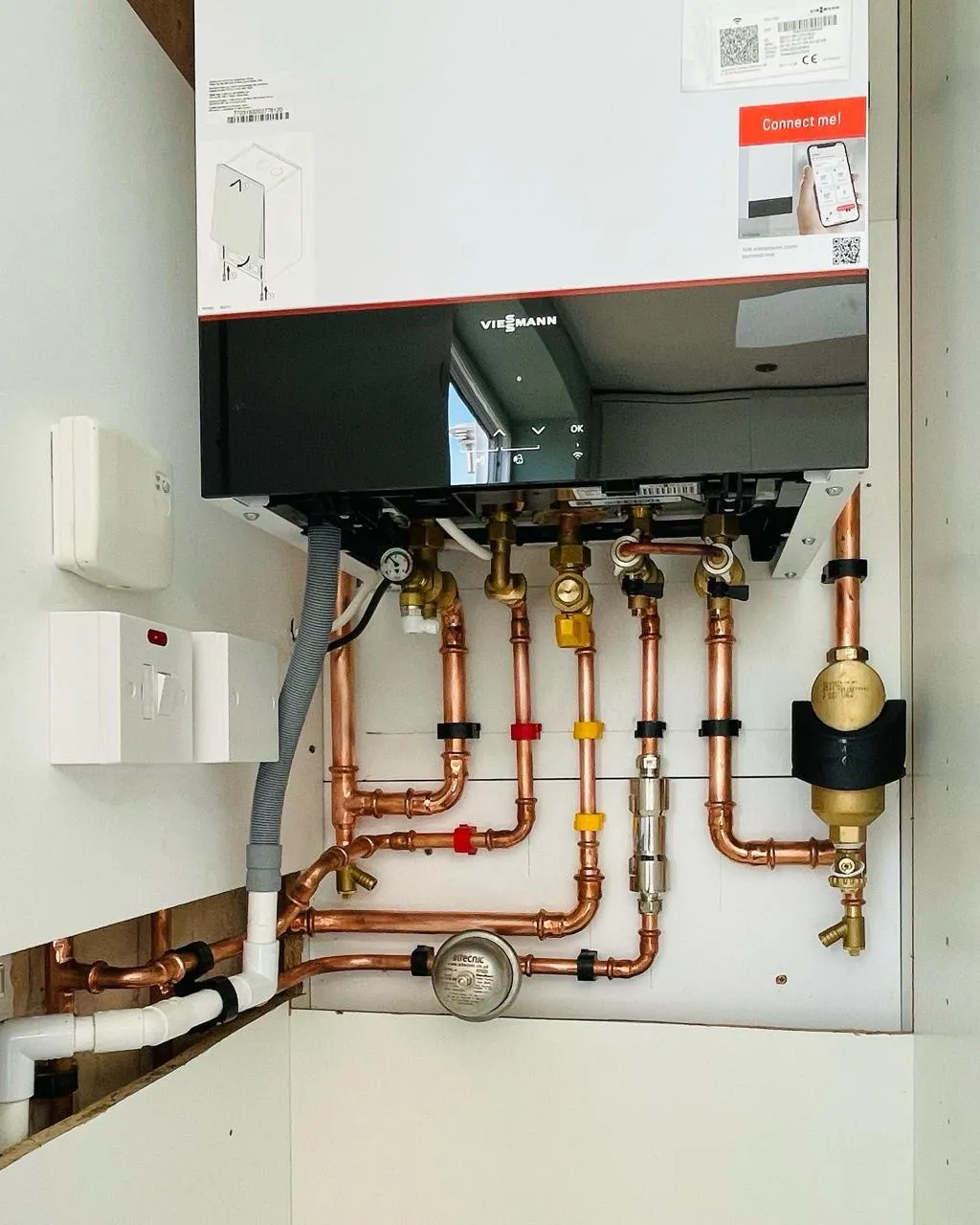 Viessmann boiler installation with labelled copper pipework and Altecnic pressure gauge inside utility unit